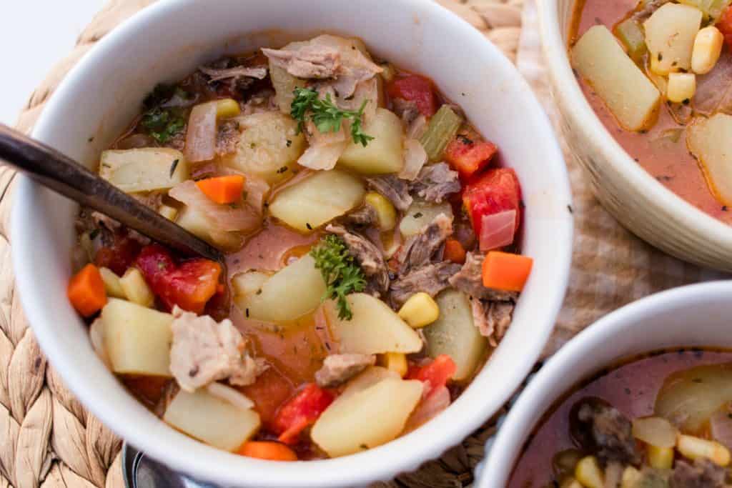 Savory pork neck bone soup in a white plate with a gold spoon.