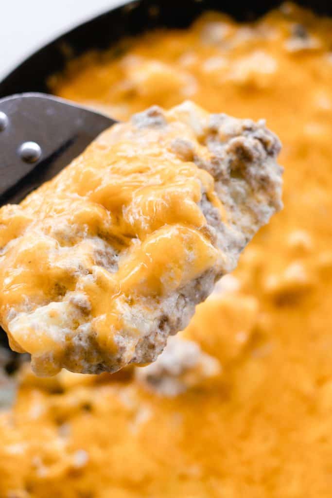 A spatula full  of cheesy venison casserole.