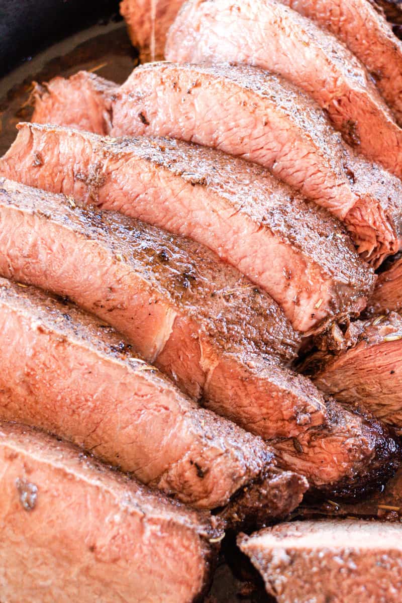 Sirloin tip roast cut into serving sized pieces in a cast iron skillet.