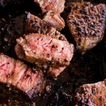 Cast iron tri tip steaks with pink juicy centers resting in a cast iron skillet.