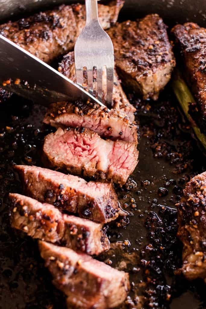 Slicing the tri tip in a cast iron skillet with a sharp steak knife.