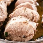 Pork tenderloin cut into medallions in a cast iron skillet.