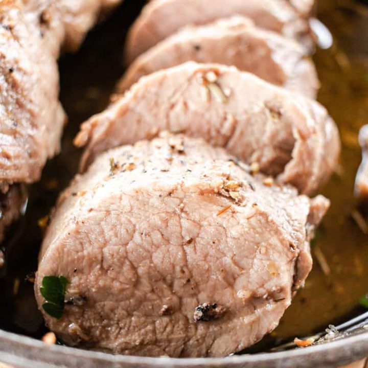 Pork tenderloin cut into medallions in a cast iron skillet.