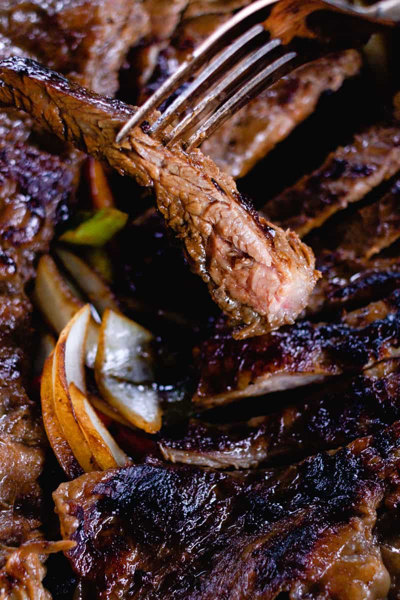 Cast iron skirt steak thinly sliced with fajita vegetables.