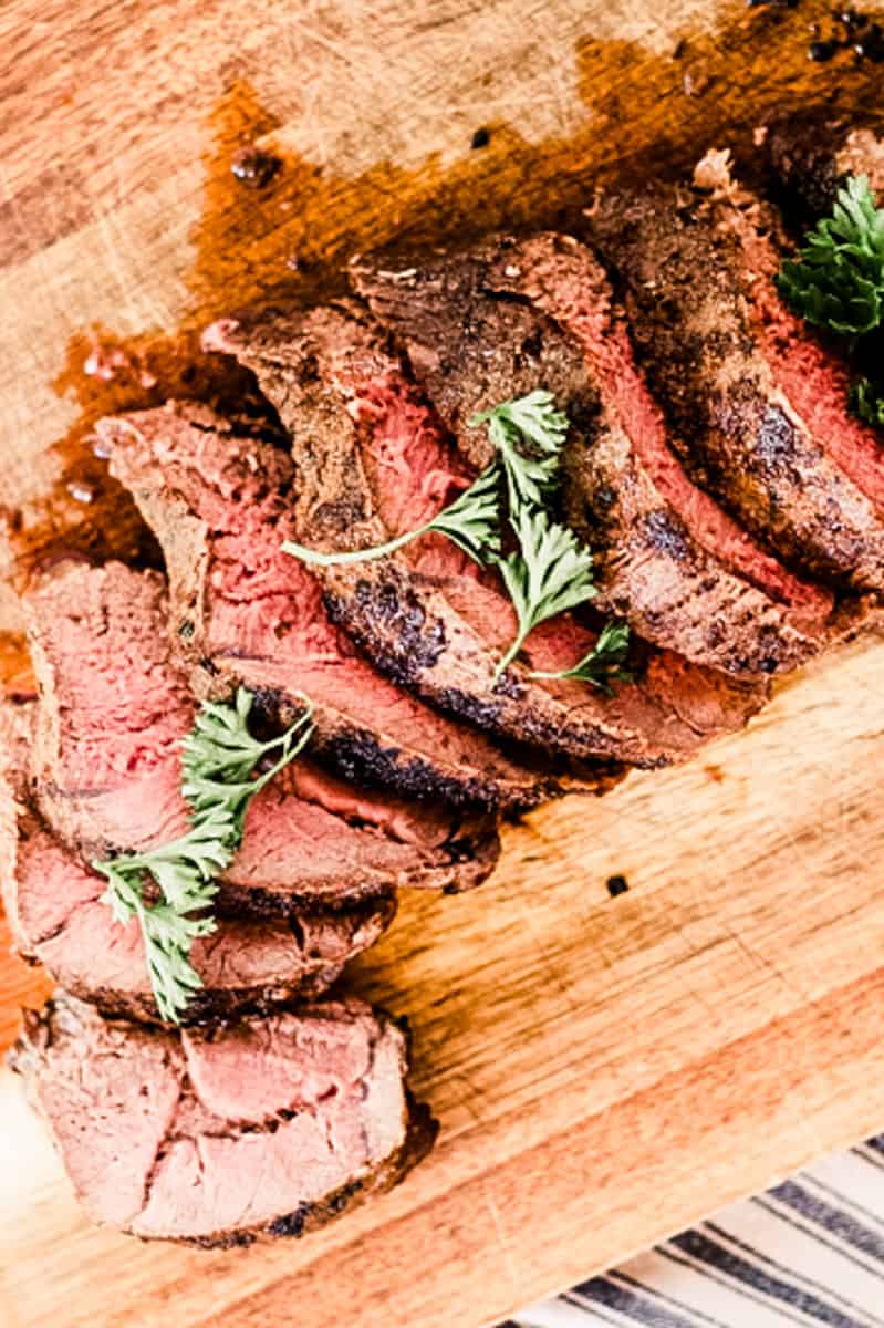 Venison backstrap cut up on a wooden cutting board.