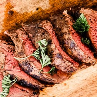 Thin sliced venison backstrap on a wooden cutting board.