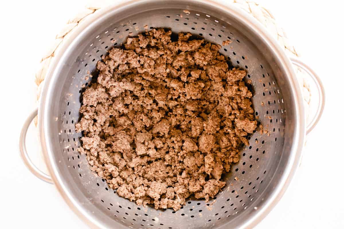 A metal colander full of boiled ground beef that has had its water drained off, ready for the next stage of meal prep.