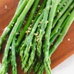 Boiled asparagus with coarse sea salt on a wooden cutting board.