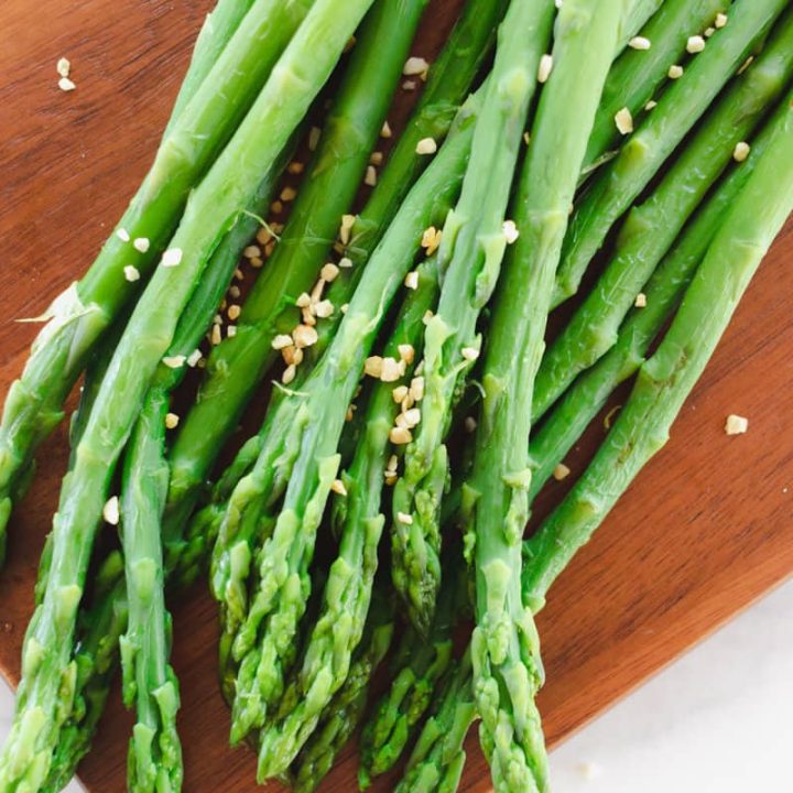 Boiled asparagus with coarse sea salt on a wooden cutting board.