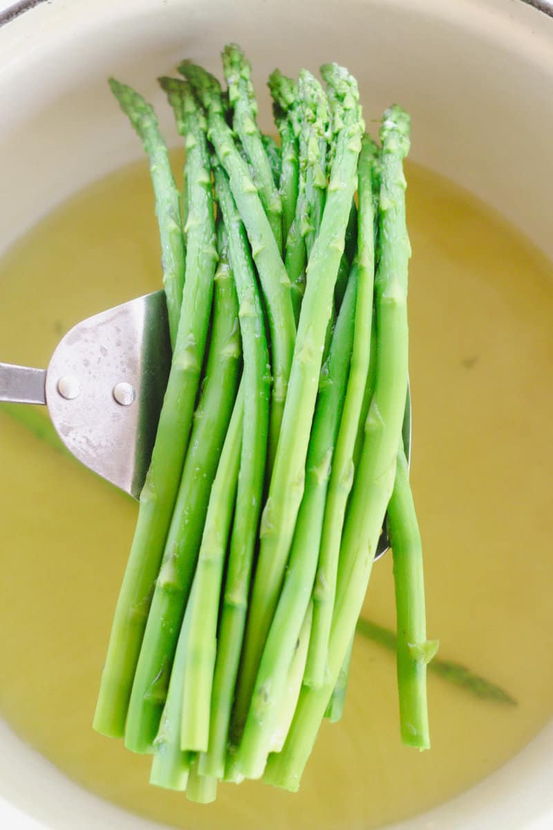 Placing fresh asparagus into a pot of boiling water.