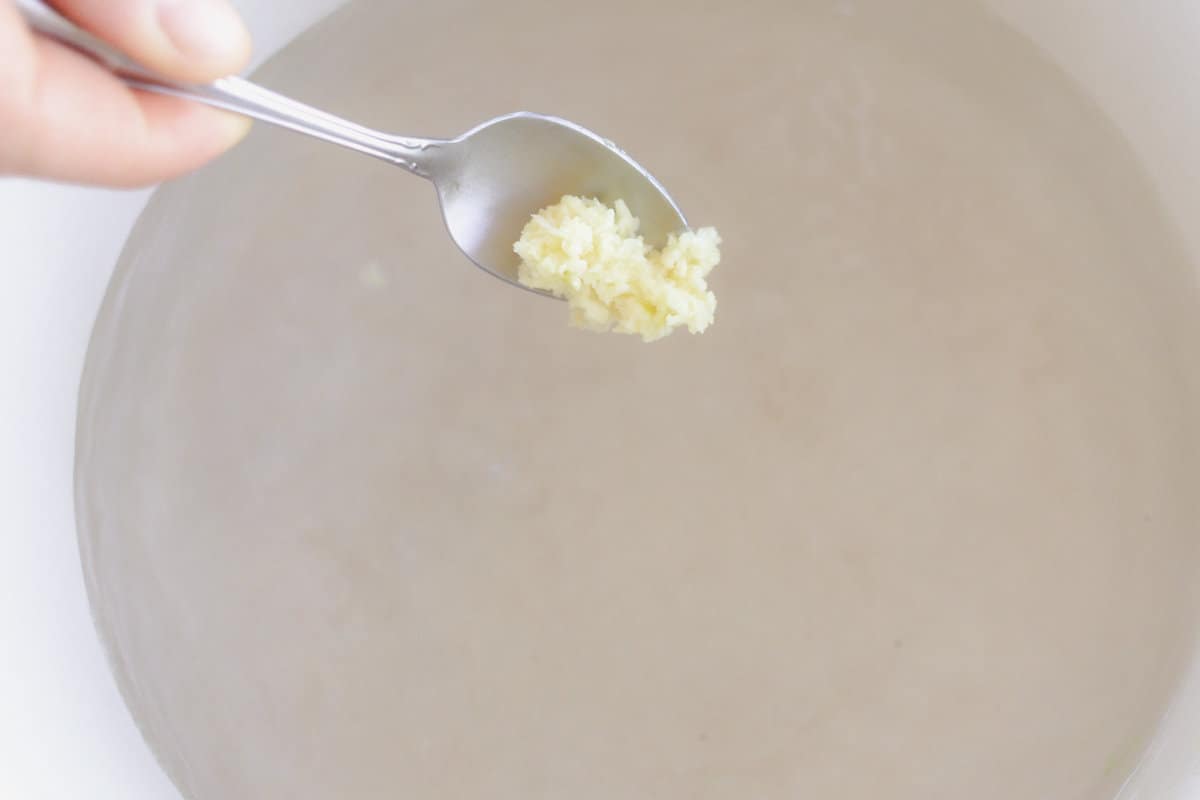 Adding minced garlic to the dutch oven.