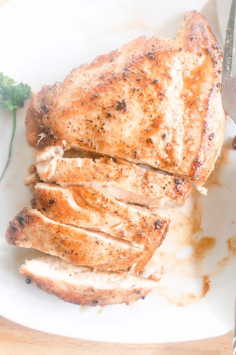 Seasoned cast iron chicken breast cut up on a white plate.