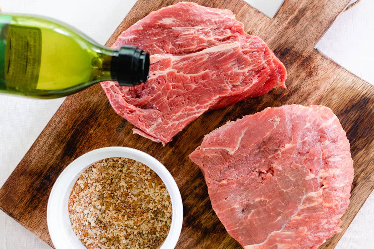 Pouring olive oil to coat the thick steaks.