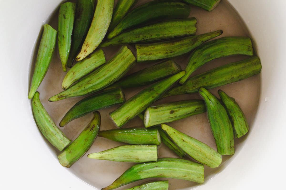 Freshly cook boiled okra cooling in a pot of cold water.