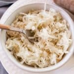 A bowl of fried sauerkraut with a spoon sticking out of it.