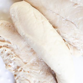 Boiled chicken tenders on a white plate.