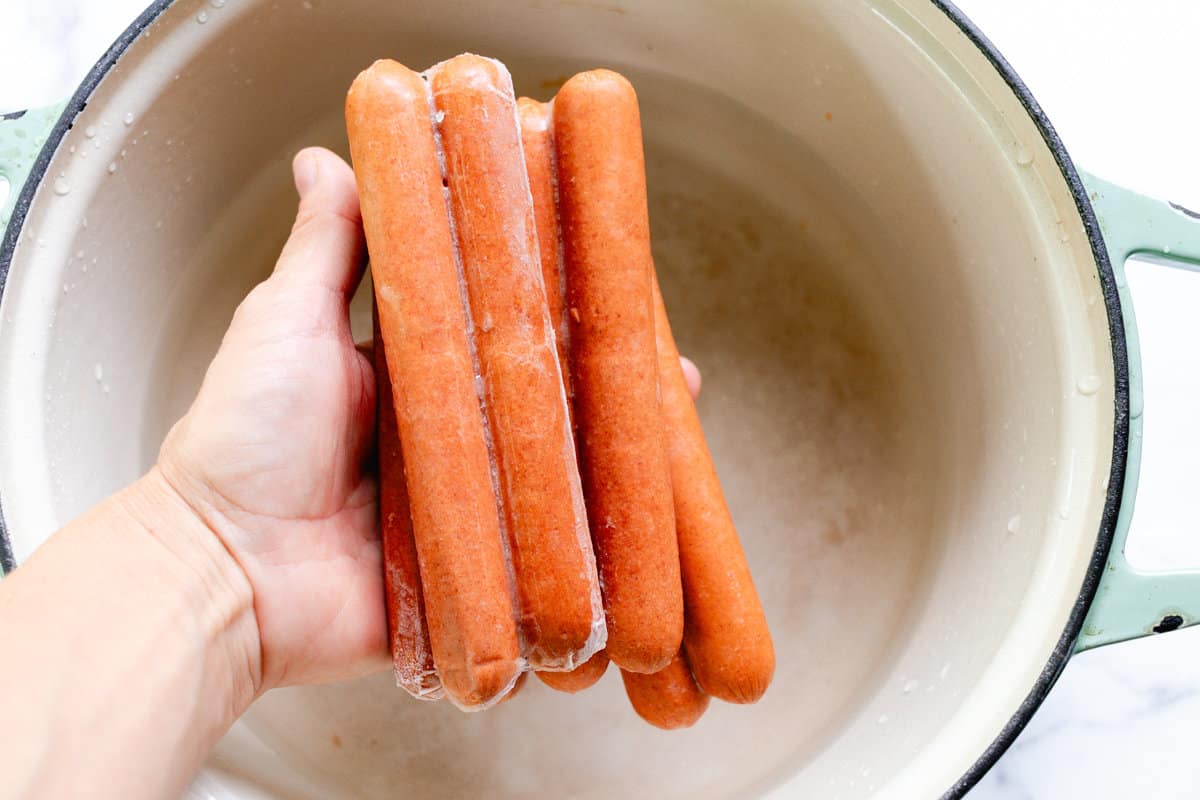 Frozen hot dogs about to go into a dutch oven filled with water.