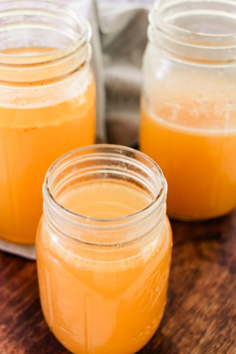 Close up view of homemade ham stock in mason jars on a wooden board.