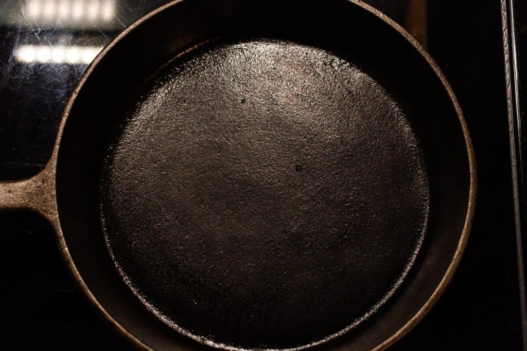 Skillet being seasoned on the stove.