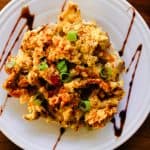 Chilli scrambled eggs on a white plate with date sauce drizzled across the top.