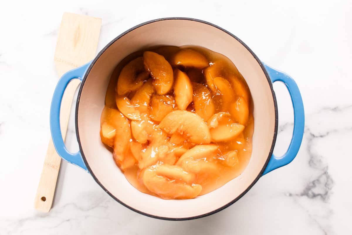 Cans of peach filling in the bottom of the dutch oven.