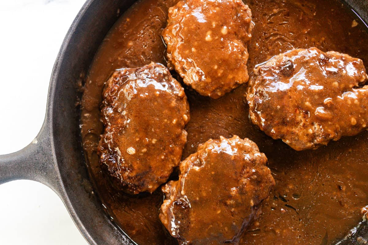 Salisbury Steak and french onion soup cooking in a cast iron skillet. 