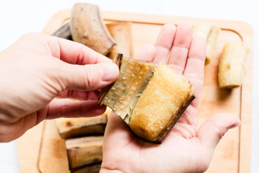 Peeling the boiled plantain after it has cooled down.