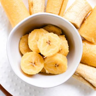 Boiled plantains sliced into thin pieces and placed into a white bowl.