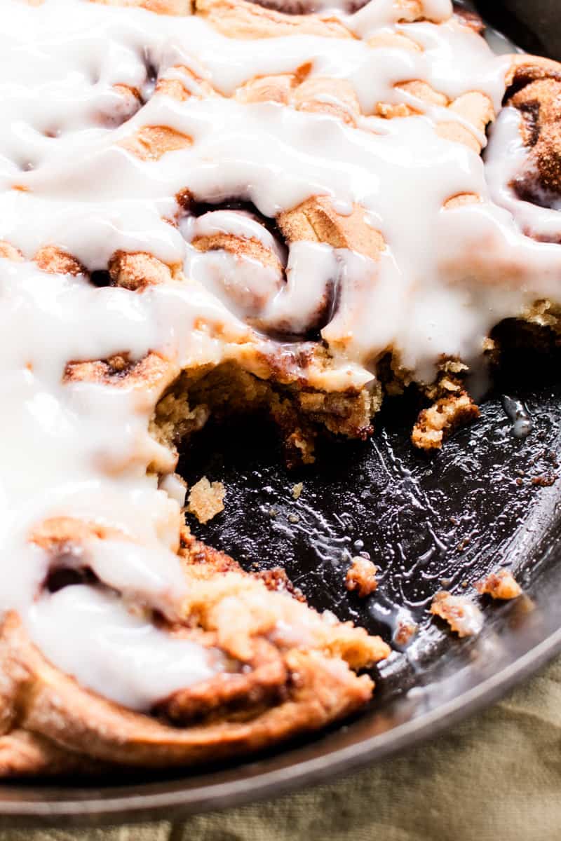 Protein cinnamon rolls with a greek yogurt glaze in a cast iron skillet.