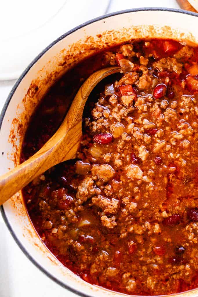 Ladling moose chili out of a dutch oven with a wooden ladle.