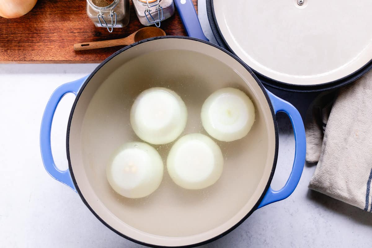 Pouring water over the onions in a dutch oven.