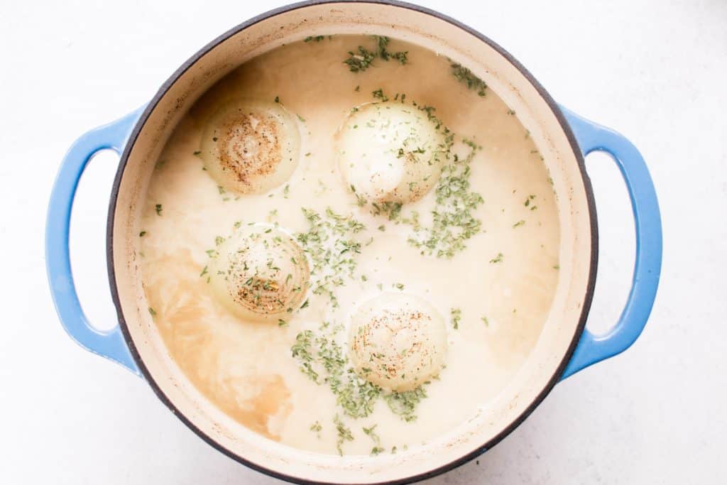 Boiled onions in a large dutch oven in a creamy broth.