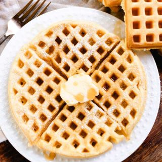 Round waffles with no milk topped with butter and maple syrup.