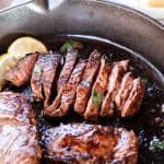 Perfectly cooked moose meat steaks sliced up thin in a cast iron skillet with a thick sear.