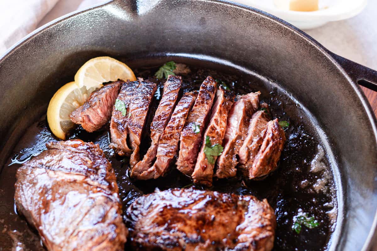 Perfectly cooked moose meat steaks sliced up thin in a cast iron skillet with a thick sear.