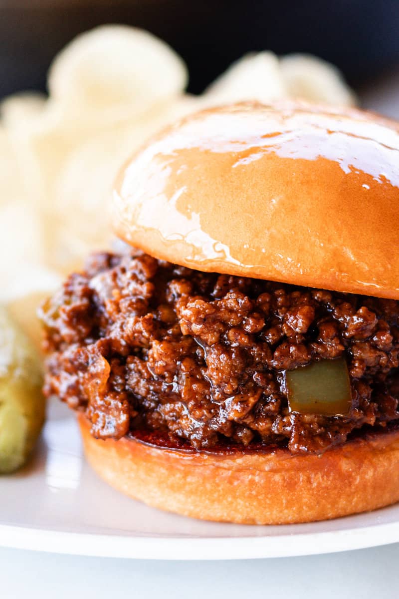 Venison sloppy joe on a toasted bun with a pickle spear next to it.