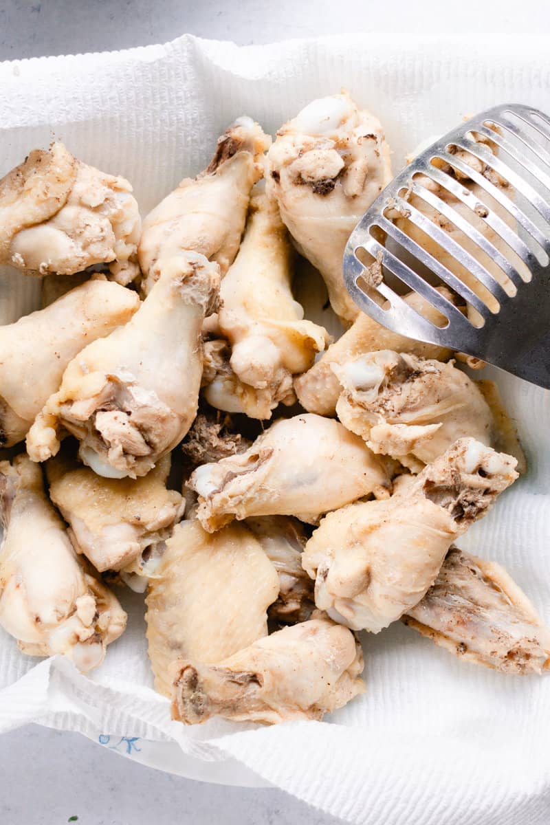 Boiled chicken wings on a paper towel-lined plate. 