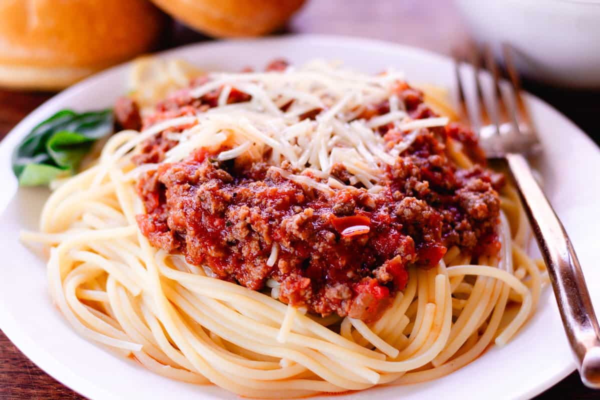 Beautiful plates venison pasta topped with white cheese on a glass plate.  