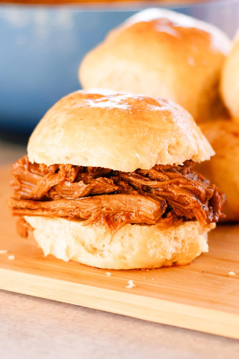 A fat sandwich made with tender shredded venison on a wooden serving tray.