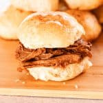 Juicy pulled venison sandwich on a homemade roll with more rolls in the background.