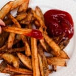 Enjoying a french fry dipped in ketchup.