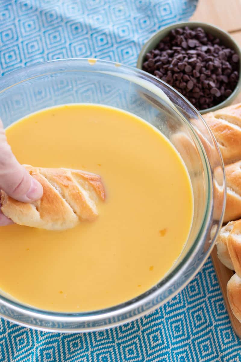 A piece of brioche bun being dipped into the mixture. 