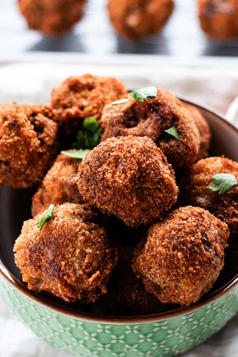 Fried ball of meat in a single sized bowl topped with fresh herbs.