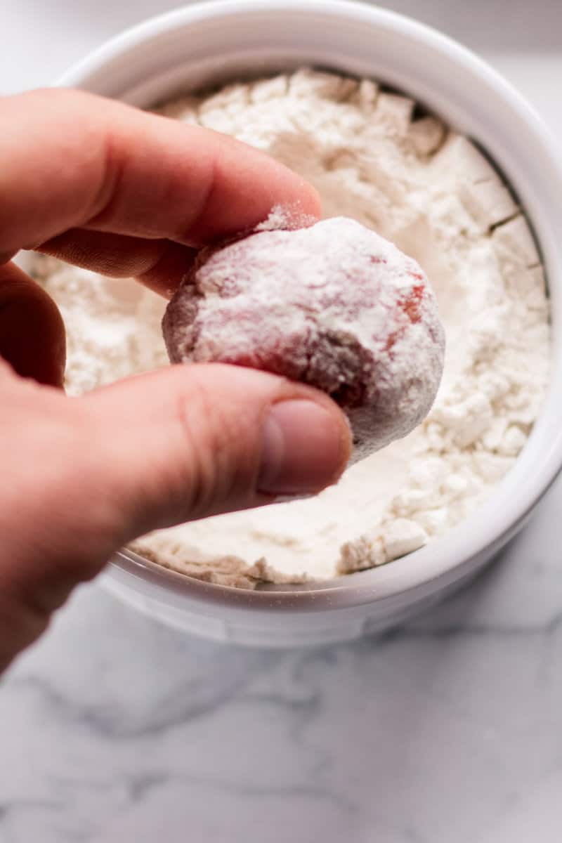 Coating the outer layer of meatballs with flour.