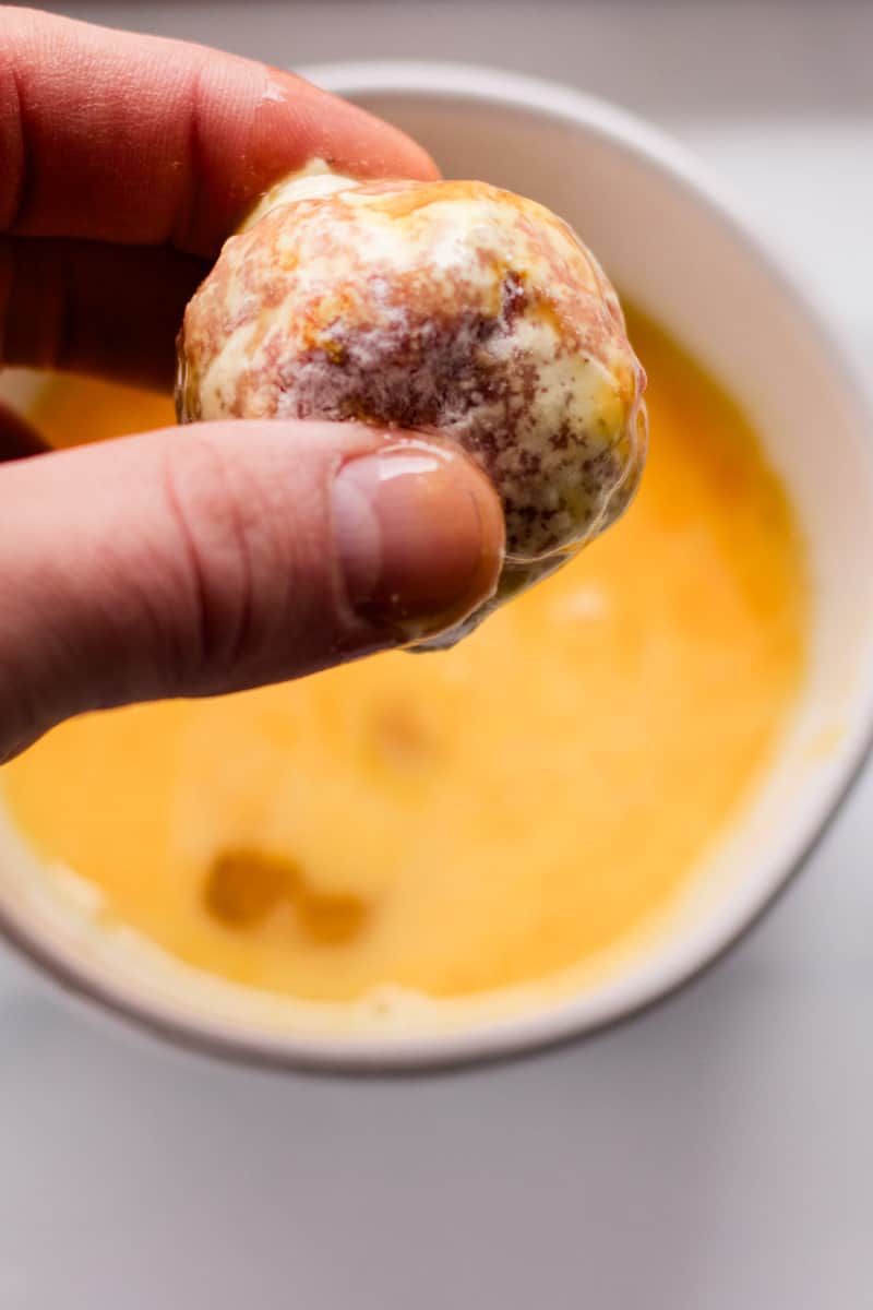 Dipping the meatball into eggs.