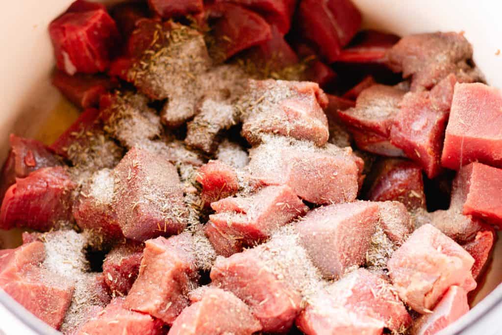 Adding the salt and pepper to the elk stew meat in a dutch oven.