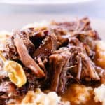 Mississippi pot roast smothered in gravy on top of a heaping pile of mashed potatoes.