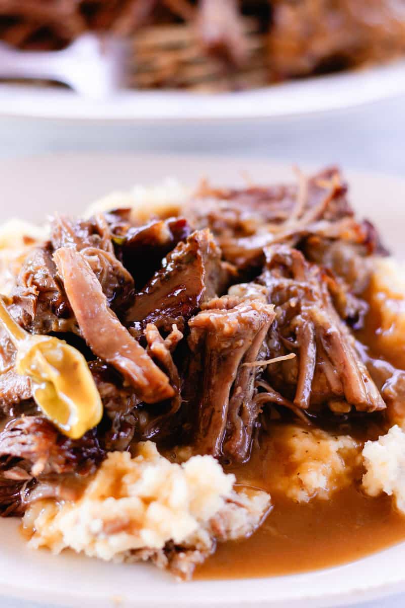 Mississippi pot roast smothered in gravy on top of a heaping pile of mashed potatoes.