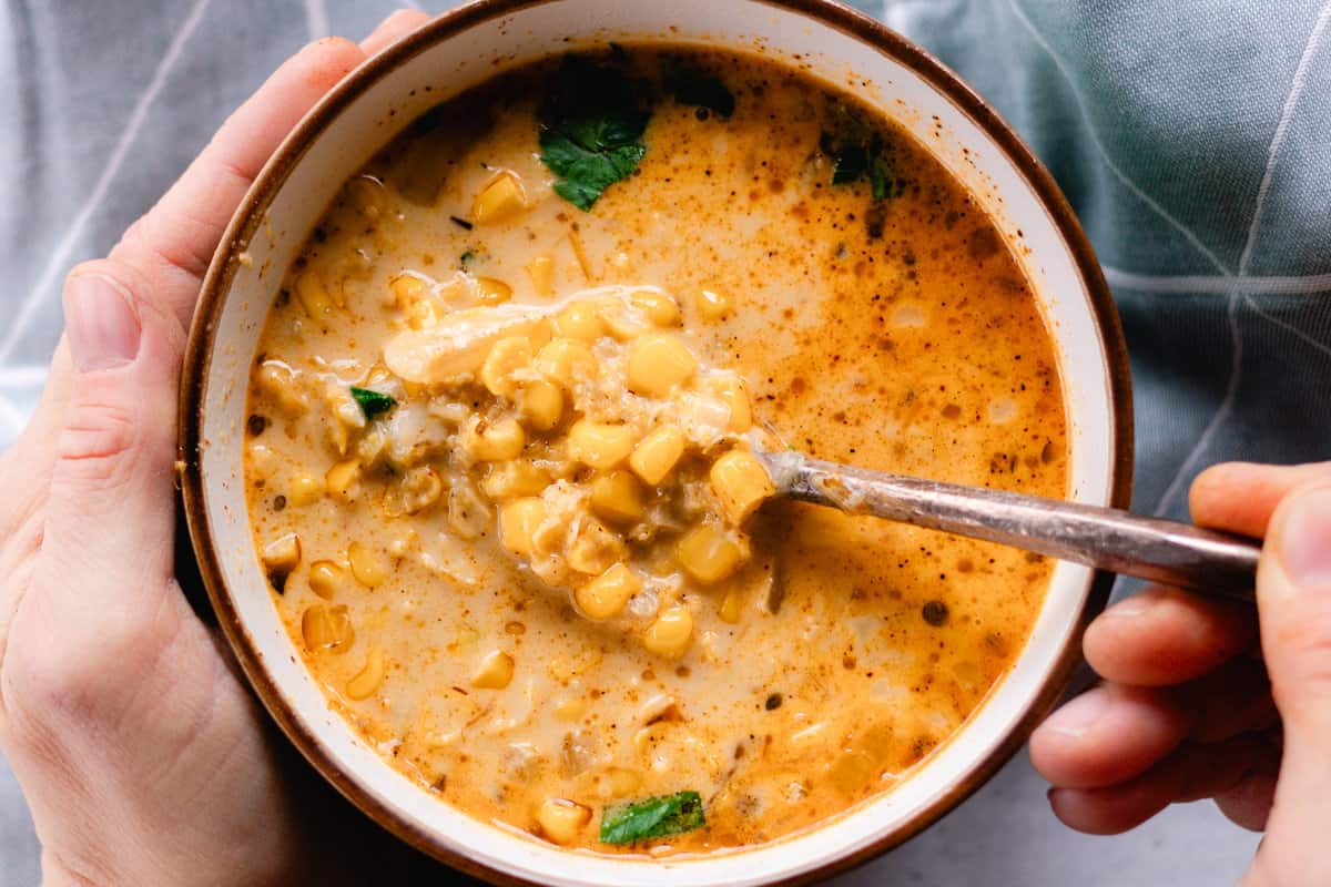 Mexican corn soup in a bowl with a spoon with a towel in the background. 