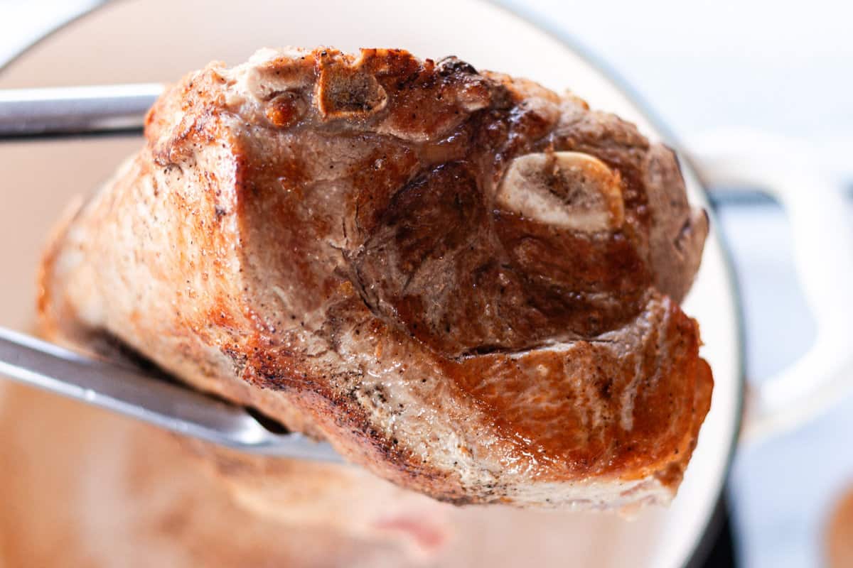 Searing the pork in a dutch oven.